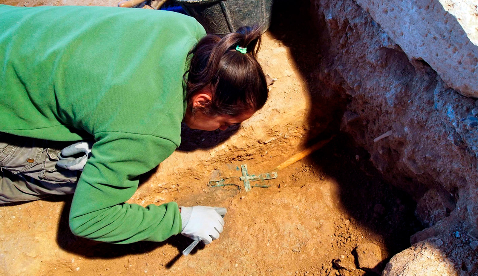 Excavación arqueológica: limpieza de una cruz de bronce recién aparecida